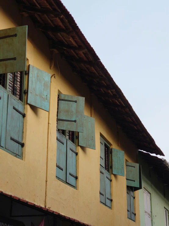 a building that has shutters on each side and some wooden bars outside