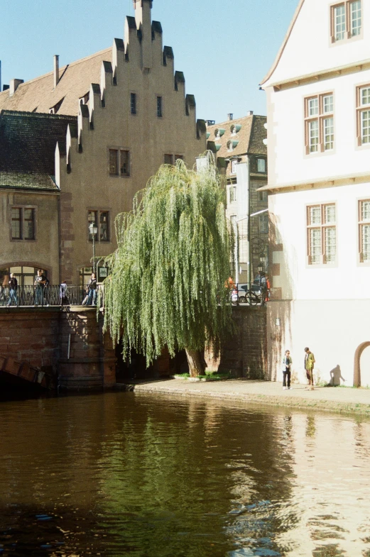 people are standing near a large river by some buildings