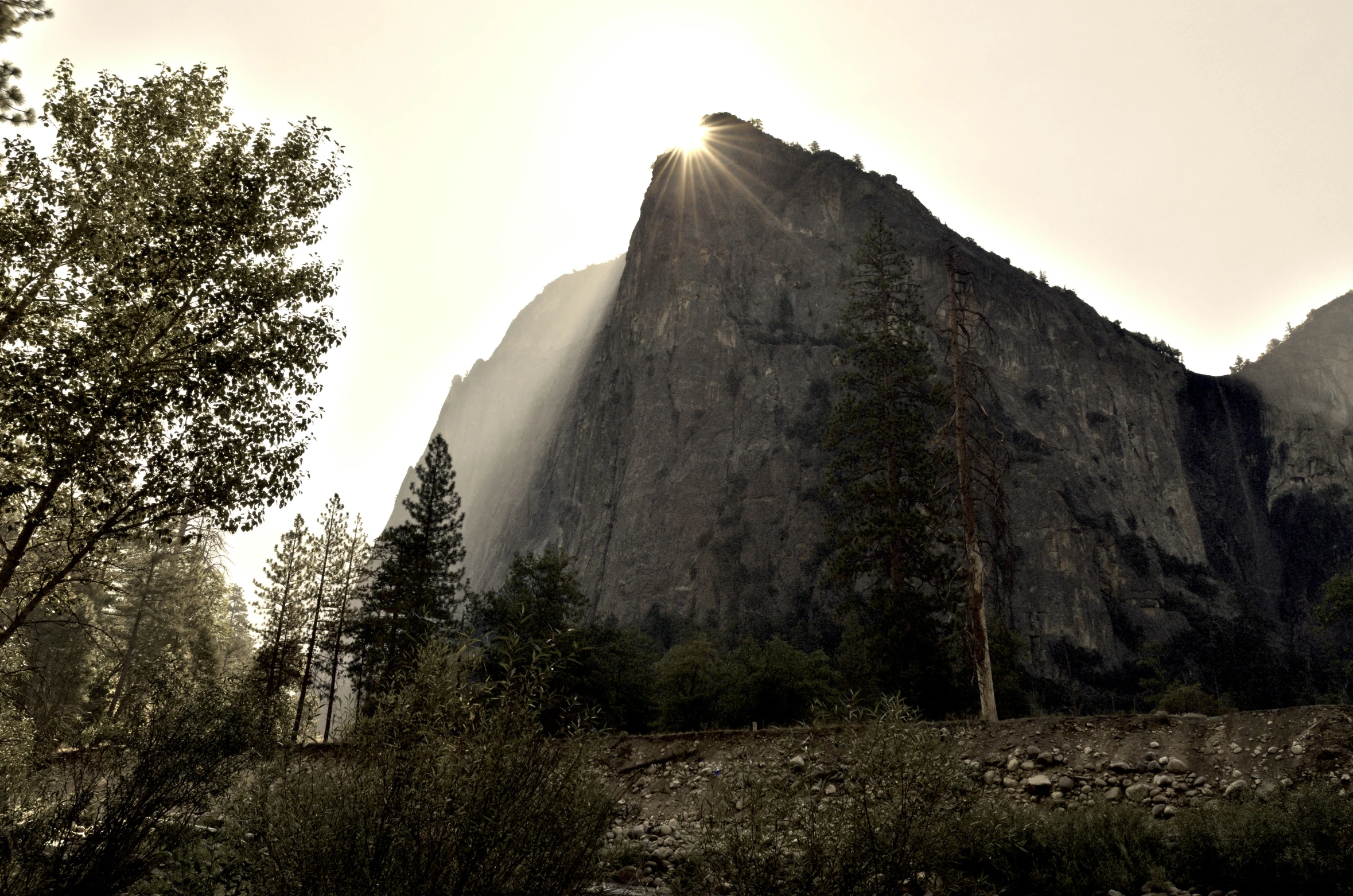 the sun peaking through the clouds near the mountains