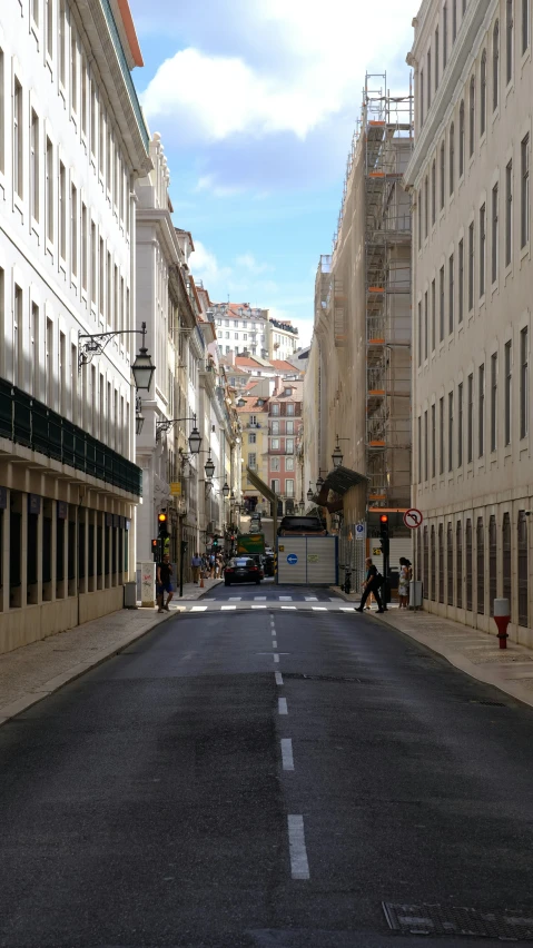 a empty street surrounded by tall buildings with scaffolding on the side of it