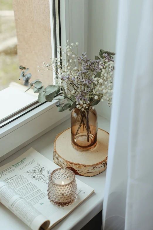 flowers are placed on top of an open book near a window