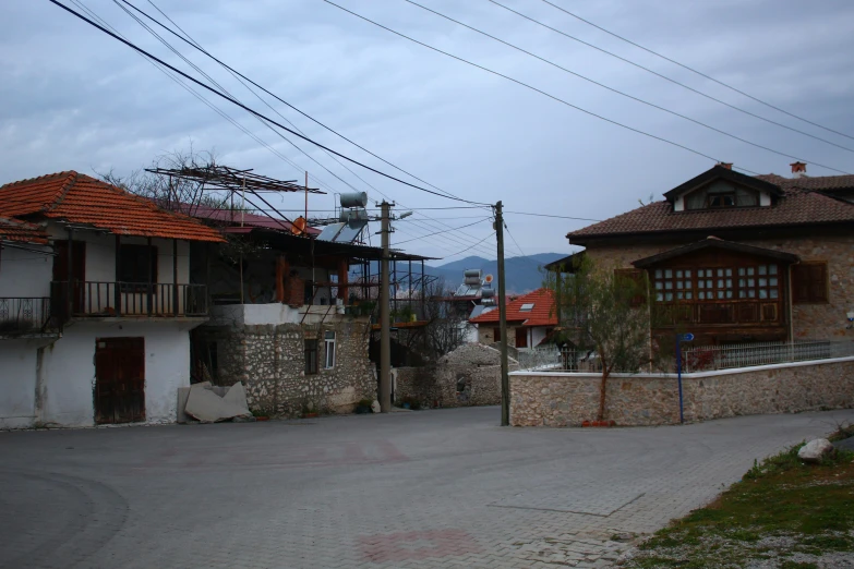 a road with two white buildings and red tiled roof