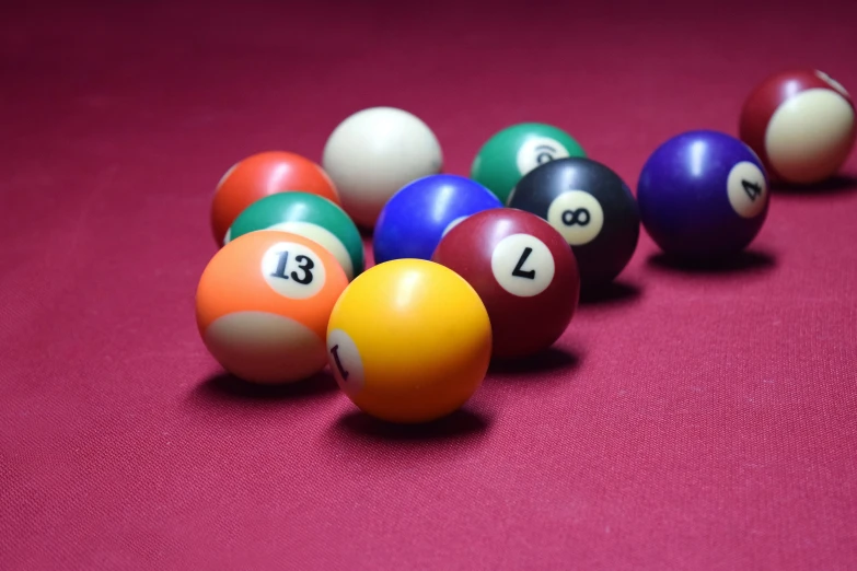 eight ball billards with numbers laid out on a pink cloth