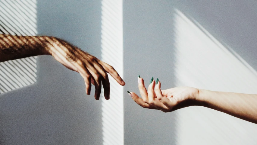 two hands reaching out towards each other while on top of them are different colored fingernails