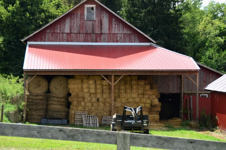 large barn with hay bails and a covered wagon