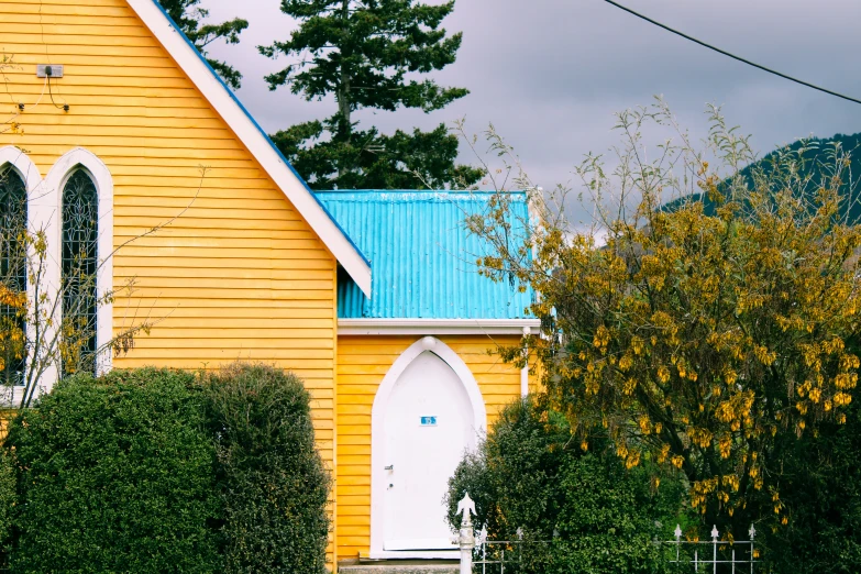 a yellow house that has green shrubs in front of it