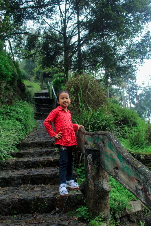 a little girl standing at the top of steps on some rocks