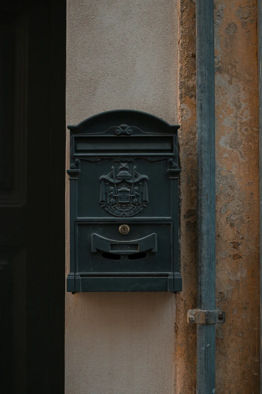 an old black mail box on a stucco building