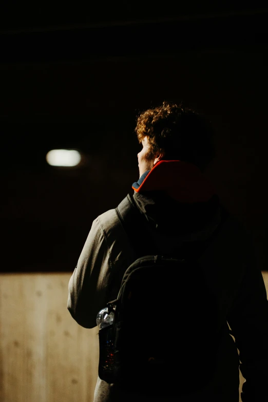 a man wearing a backpack stares into the distance