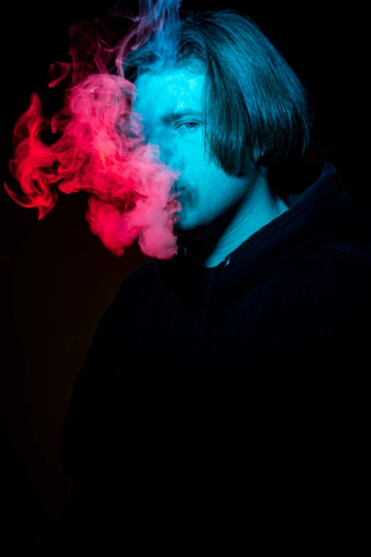 man with hoody, in front of a colored background of smoke