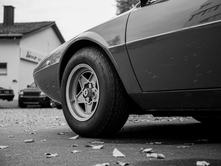 a black and white pograph of the front tire of a sports car