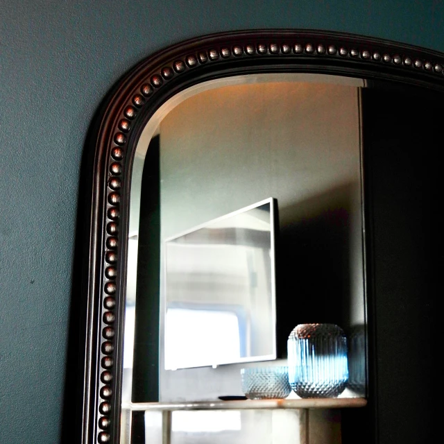 a mirror that is reflecting a room with shelf in it