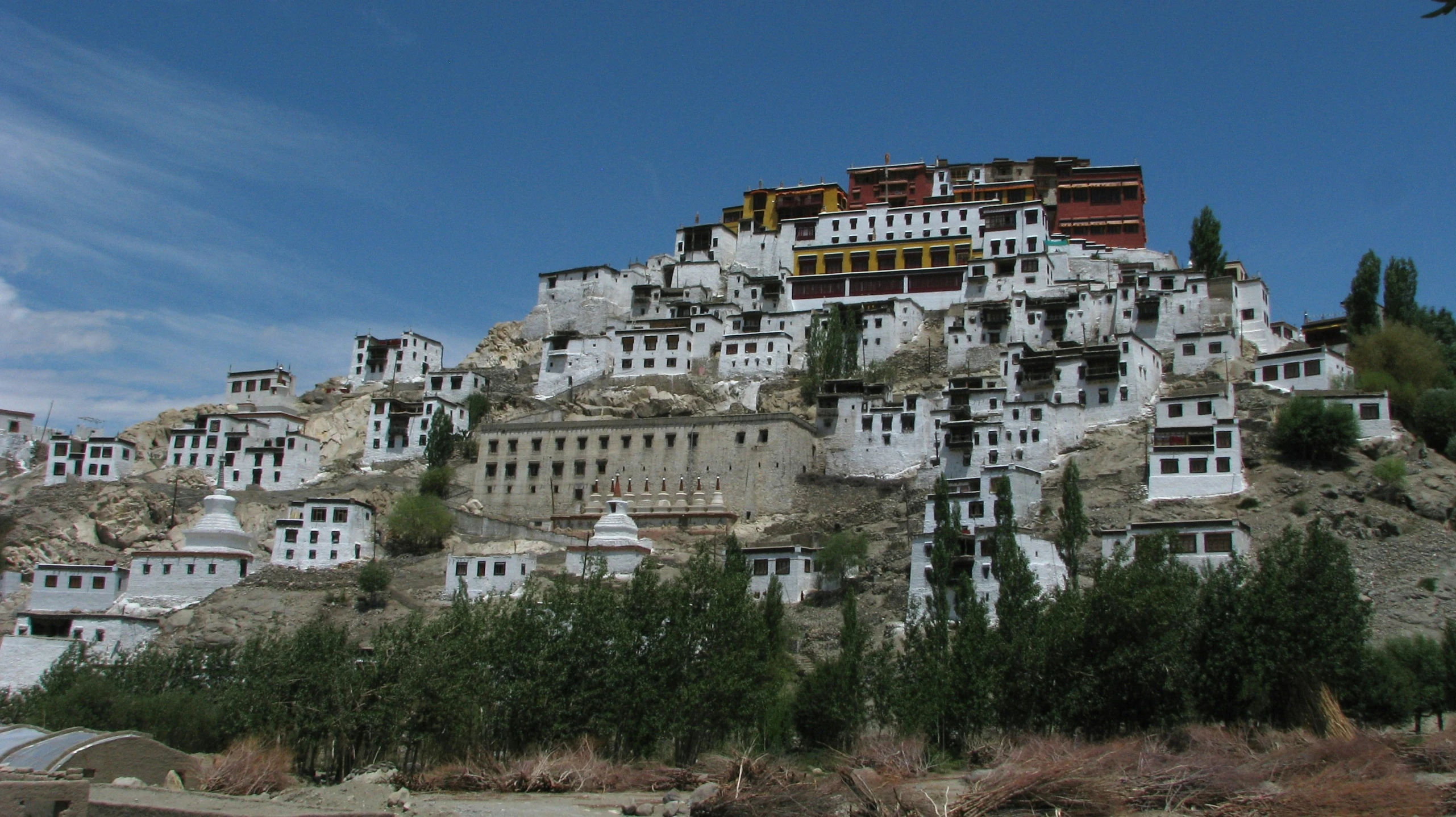 white buildings are on a cliff near trees