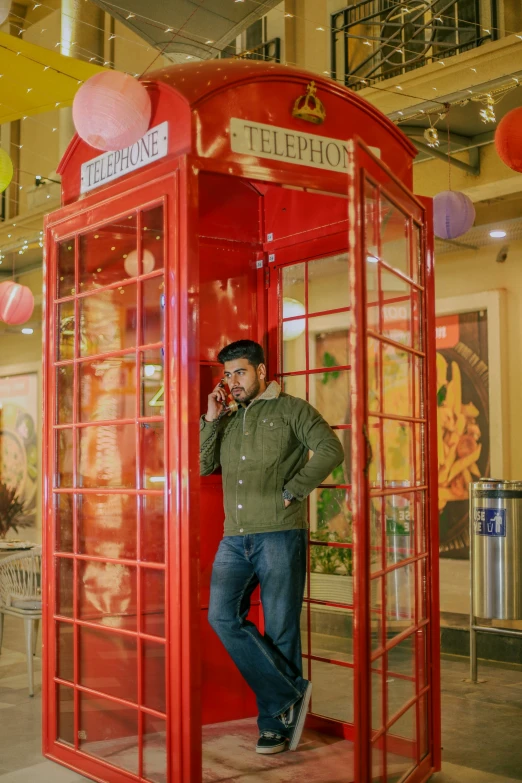 the man is standing next to the red telephone booth