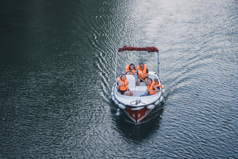 a small boat with two people in orange life jackets traveling across water