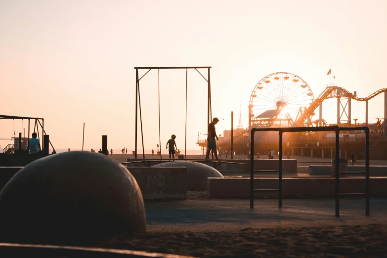 people walking down the beach near a ferris wheel at dusk