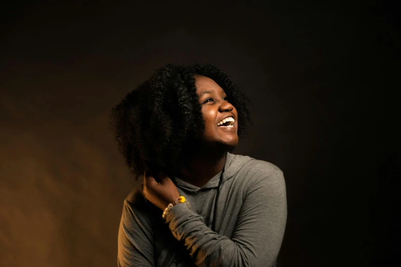 a young black woman smiling with a dark background