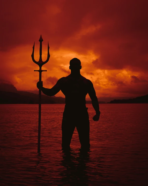 a man stands alone in the water with a crucifix in his hands