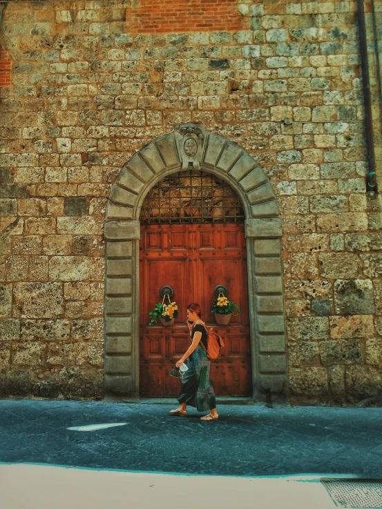 a woman is walking down the street past a red doorway