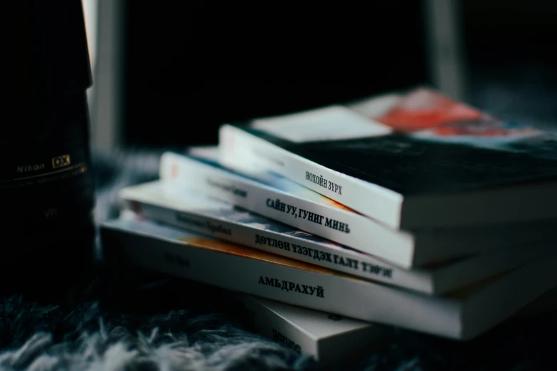 several books in a stack are next to a bottle