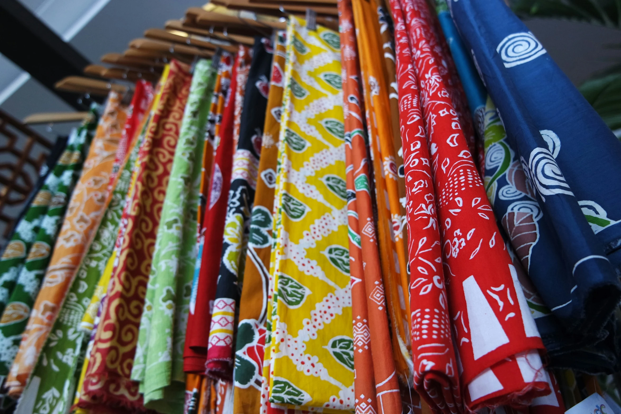 bright, colorful fabrics hang from a line in a store