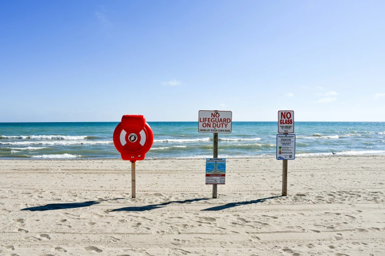 a beach with signs on each pole in the sand