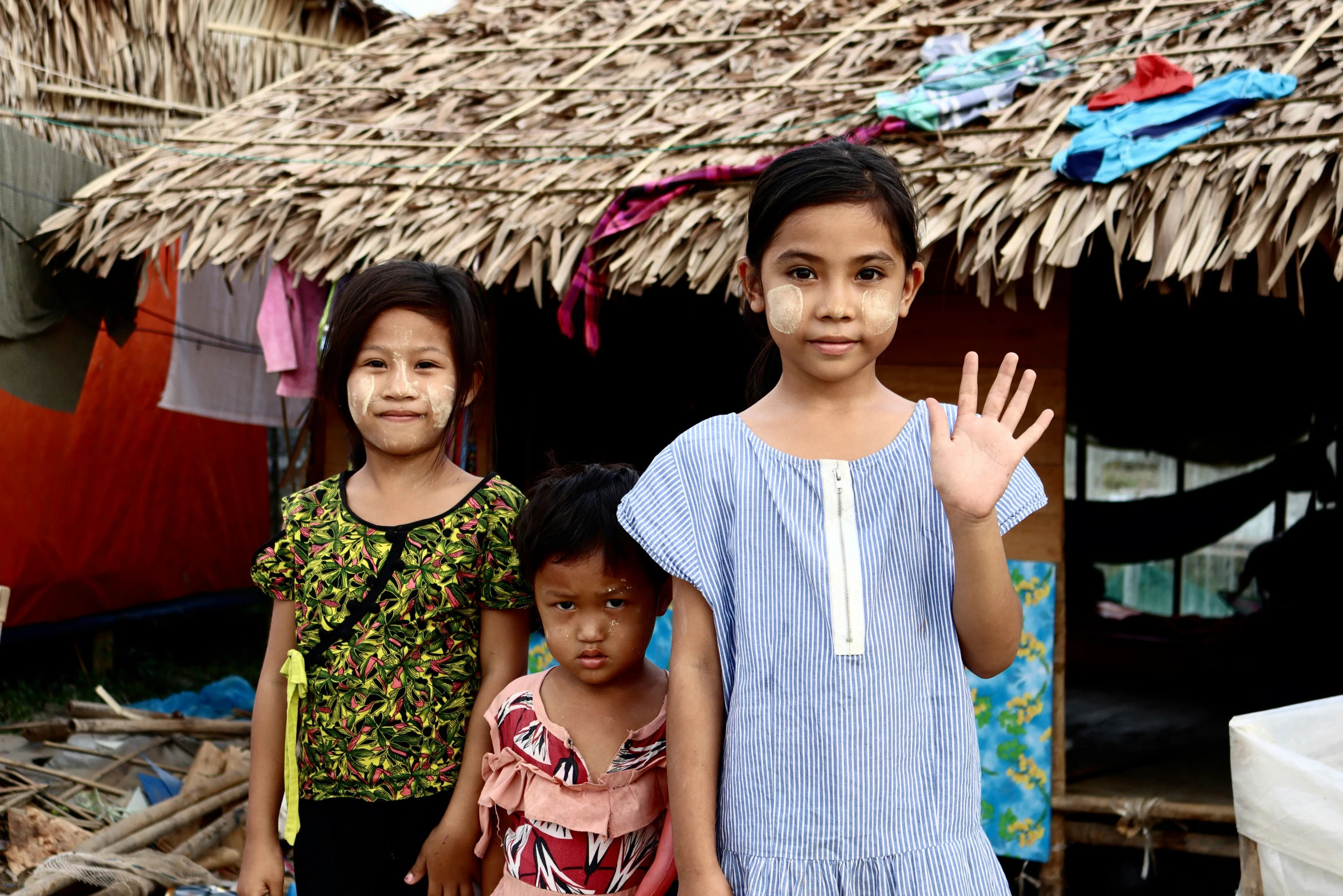 four s in front of a hut with grass roof and dryer