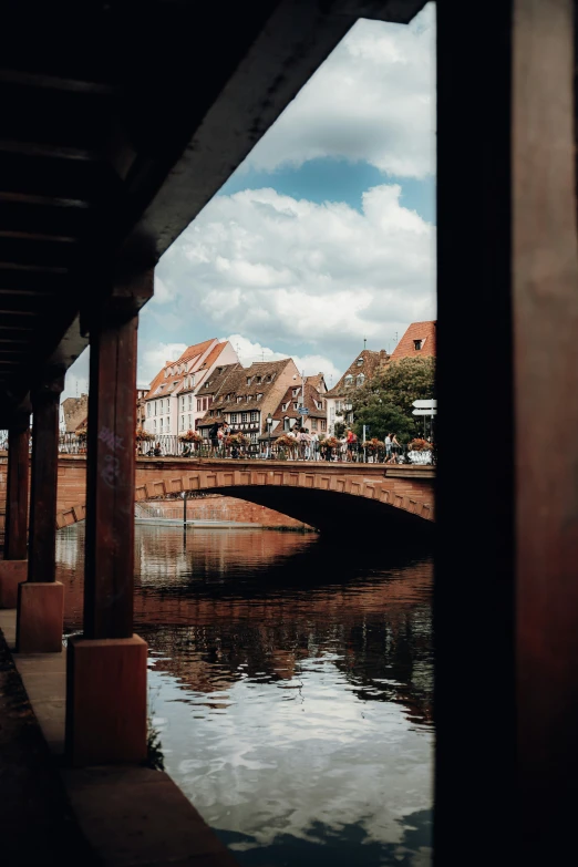 an old bridge over some calm waters and lots of red brick buildings in the background