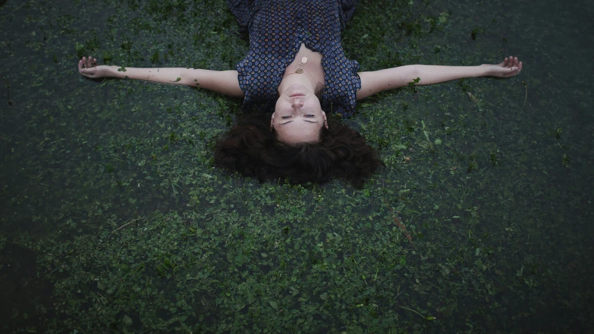 woman in dress laying on ground with head above grass