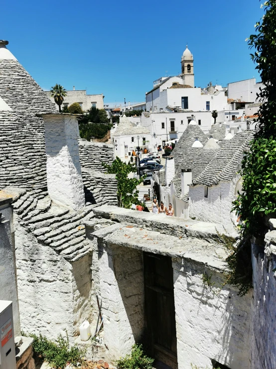 a narrow alley with stone buildings and rooftops in the distance