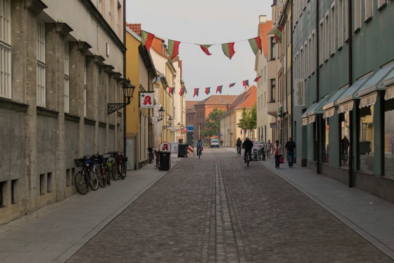 a cobble stone street leading into some building with bikes parked at both sides