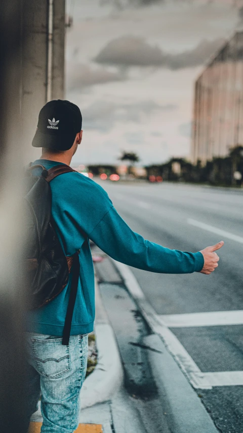 a person with a backpack standing next to a street