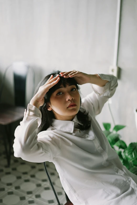 a woman is standing up holding her hand to her hair