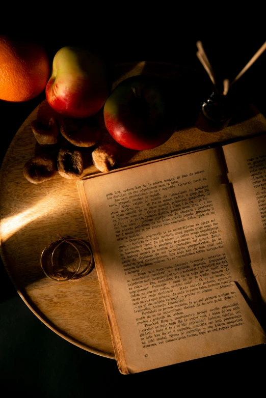 some fruit on top of a book and two oranges