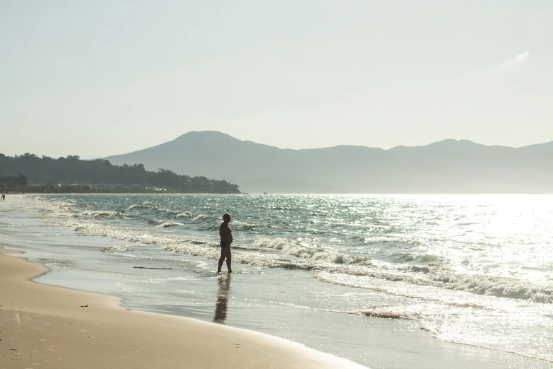 a person is walking along the water at the beach