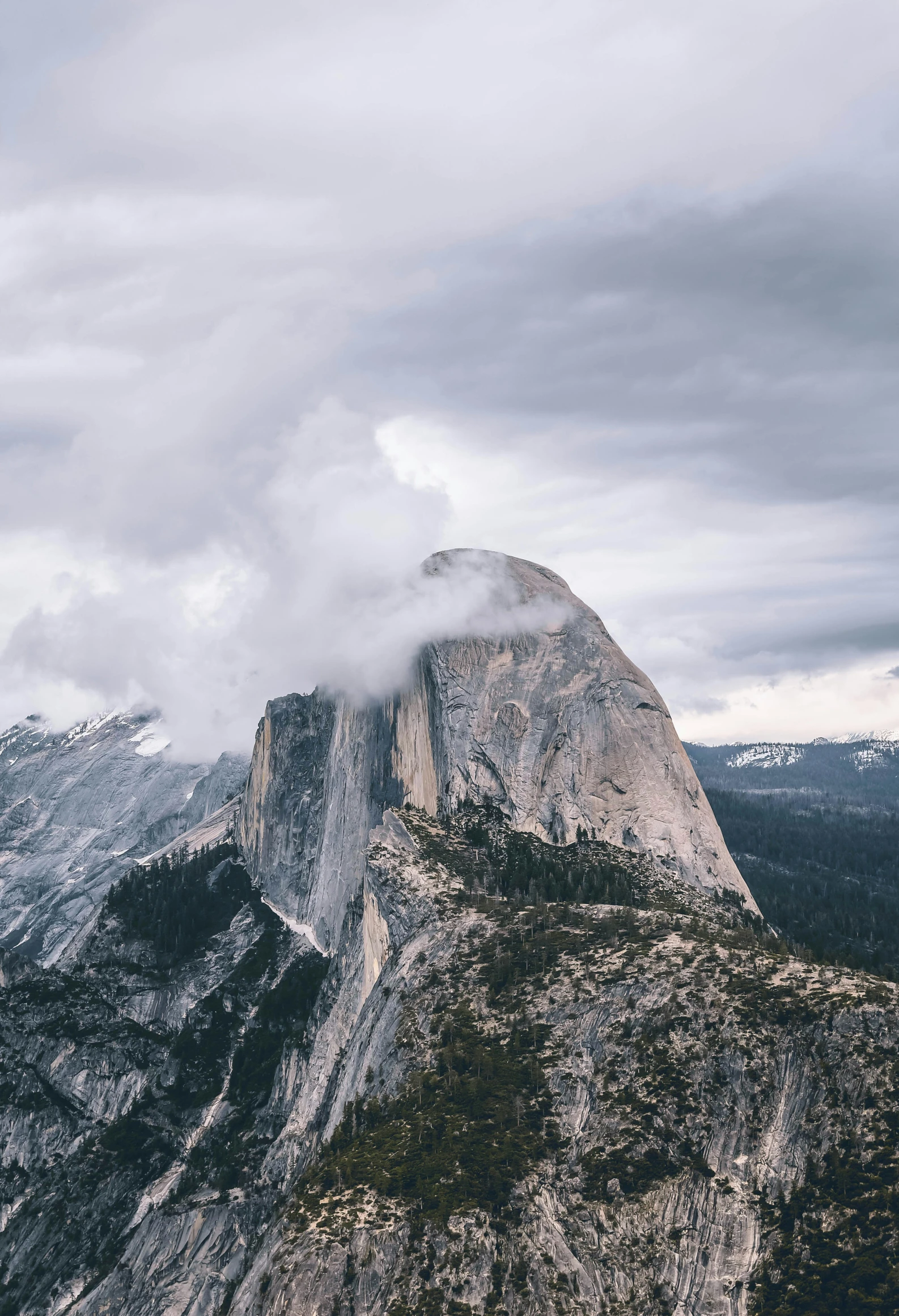 clouds hovering over the top of a mountain on a cloudy day