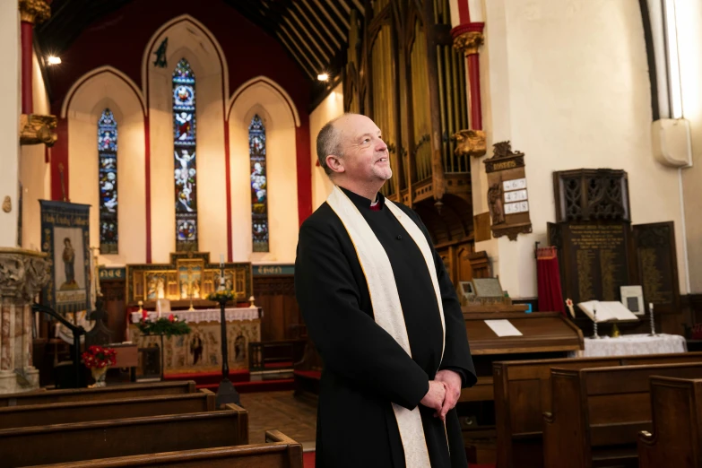 a priest standing inside an empty church looking into the distance