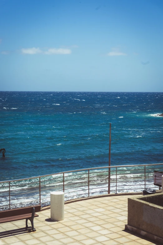 a view from a rooftop with ocean and a bench