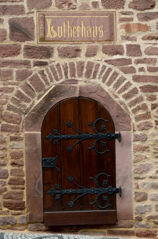 an arched wooden door has an inscription on it