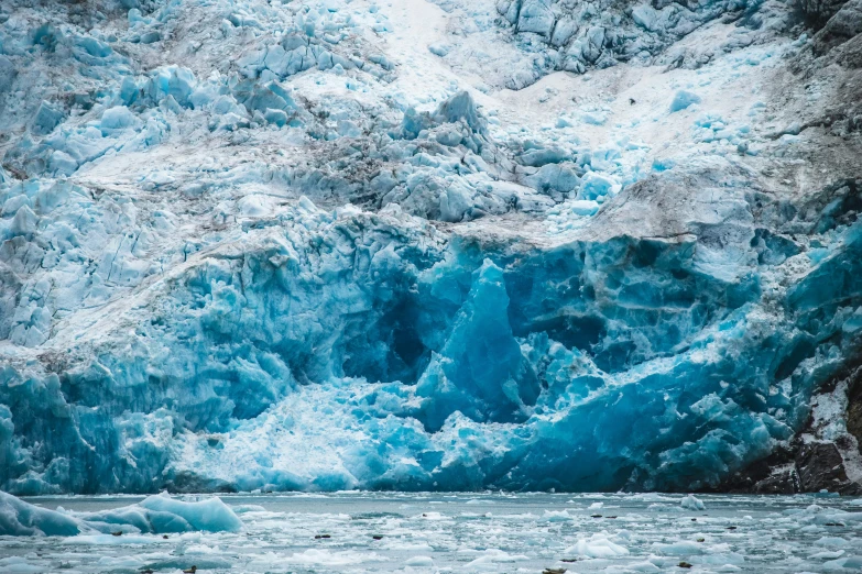 an icy mountain next to water with ice