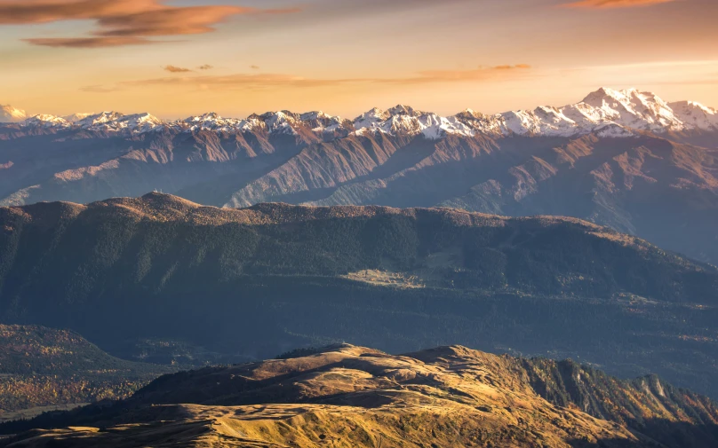 view from the top of a mountain to snowy peaks in a sunset