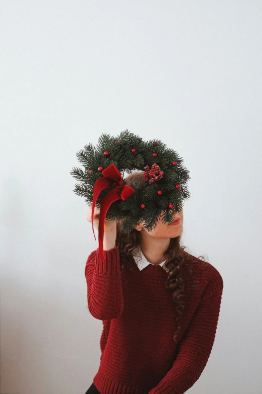 a woman in red is holding her hat up to her head