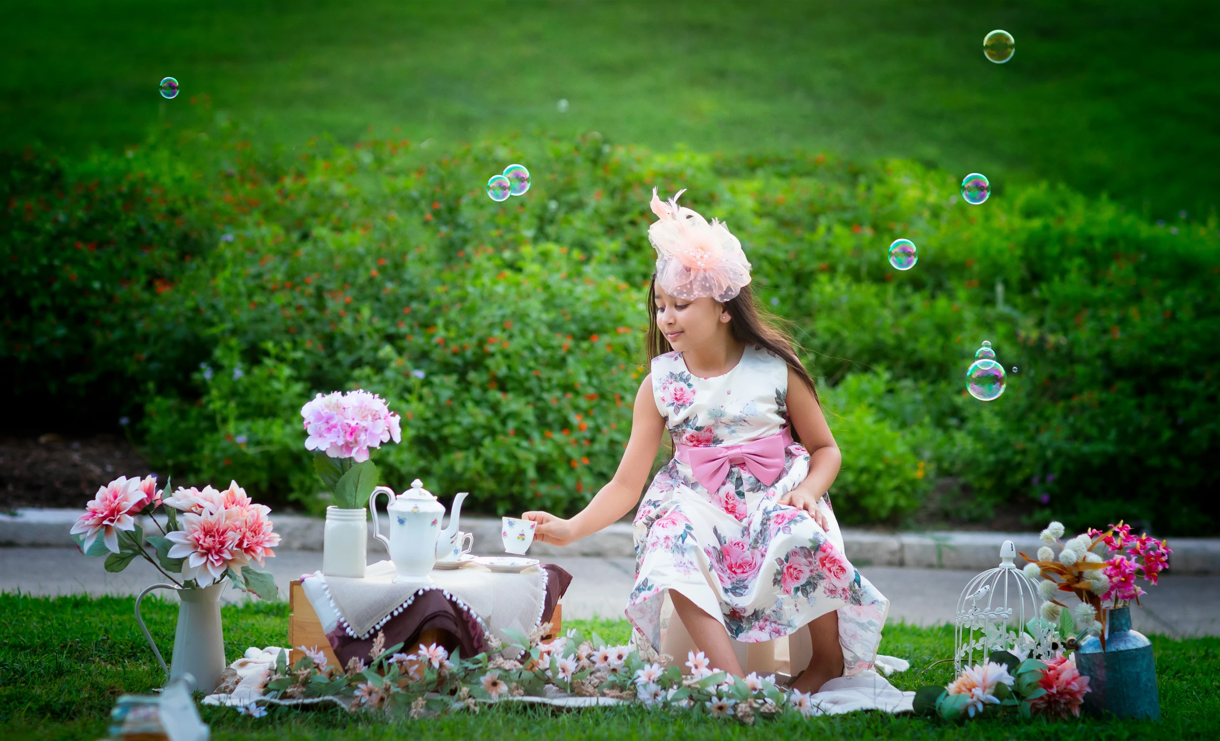 a little girl is sitting on the grass near some flowers