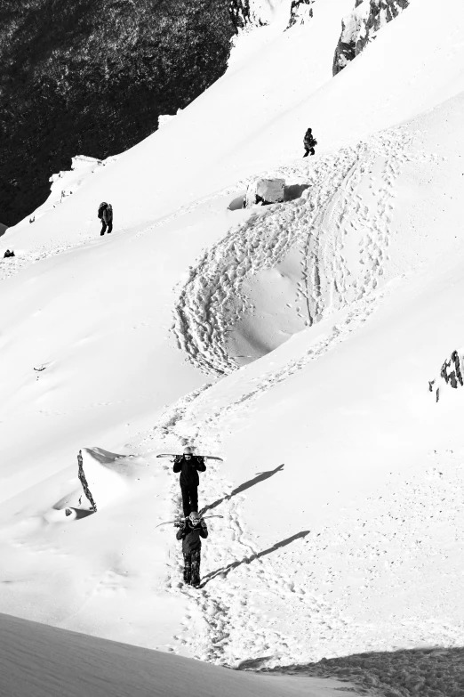 black and white po of people walking up to the top of a snowy hill