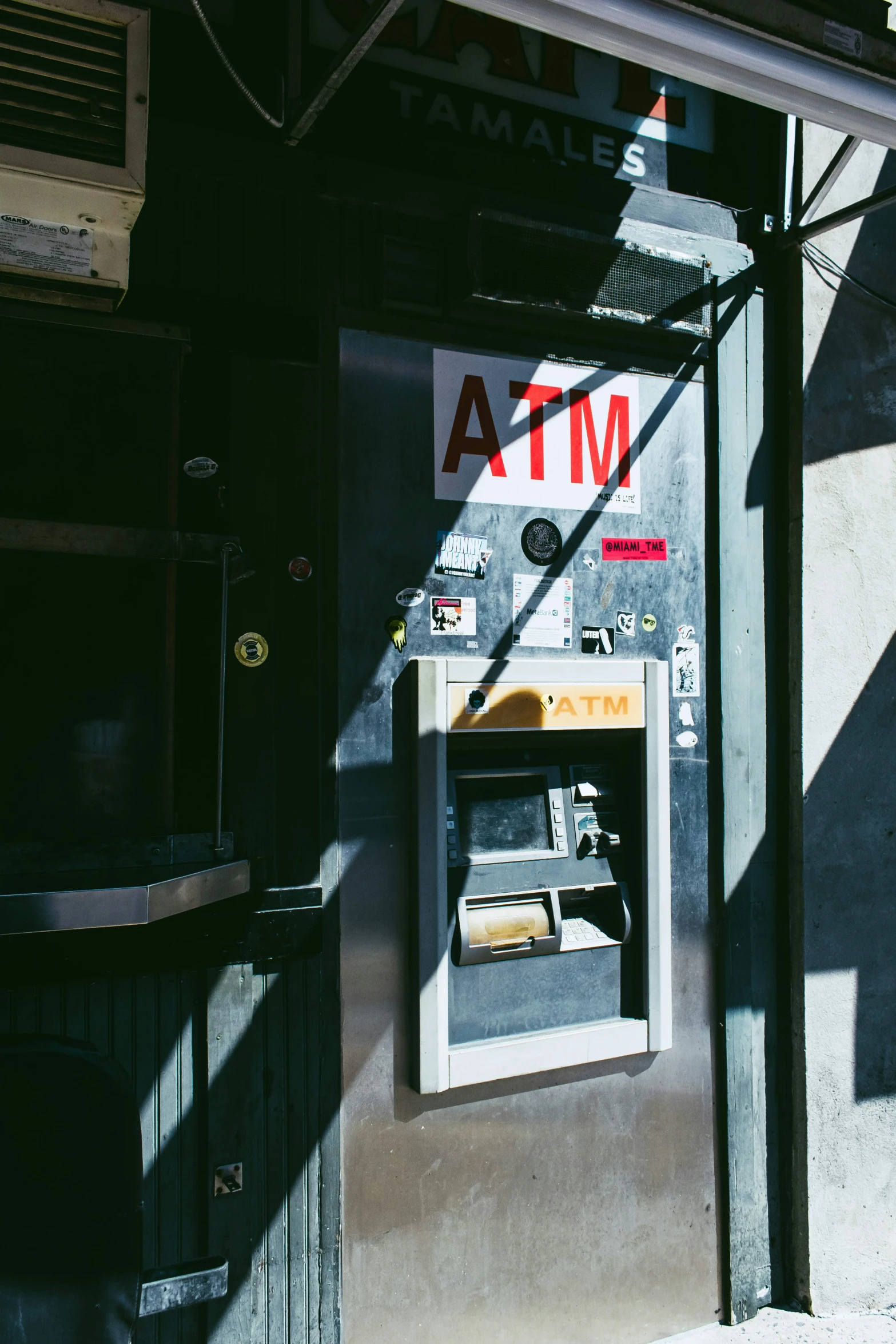 a atm on the side of a building with a shadow from it