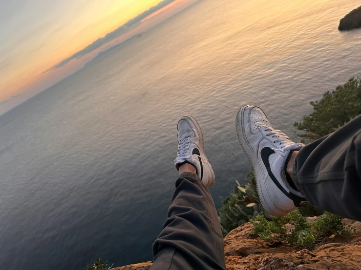 a person with their feet up on top of a cliff overlooking the water