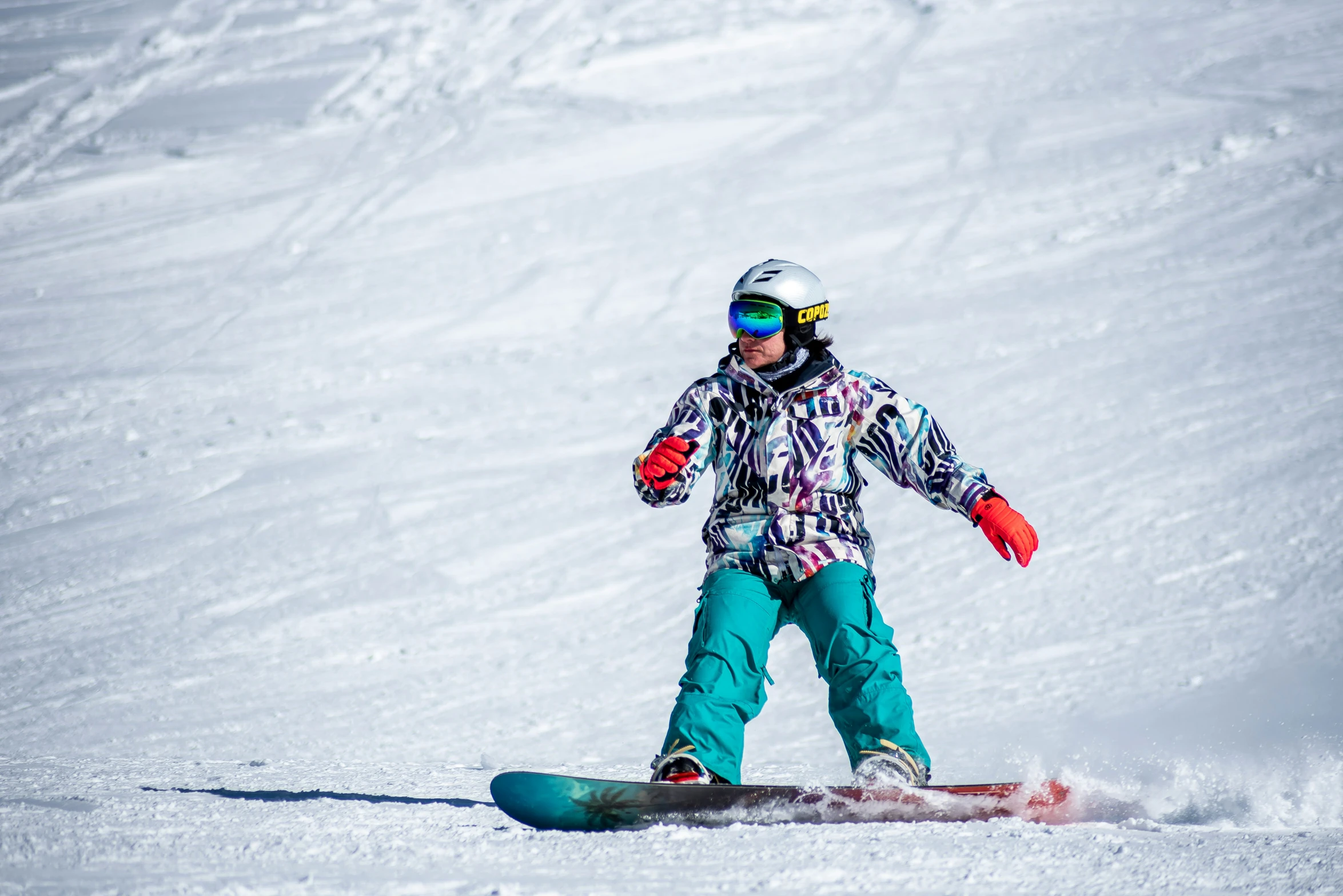 a person snowboarding down a snowy slope on a sunny day