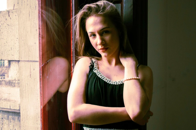 a young woman leans against the front window of an old building