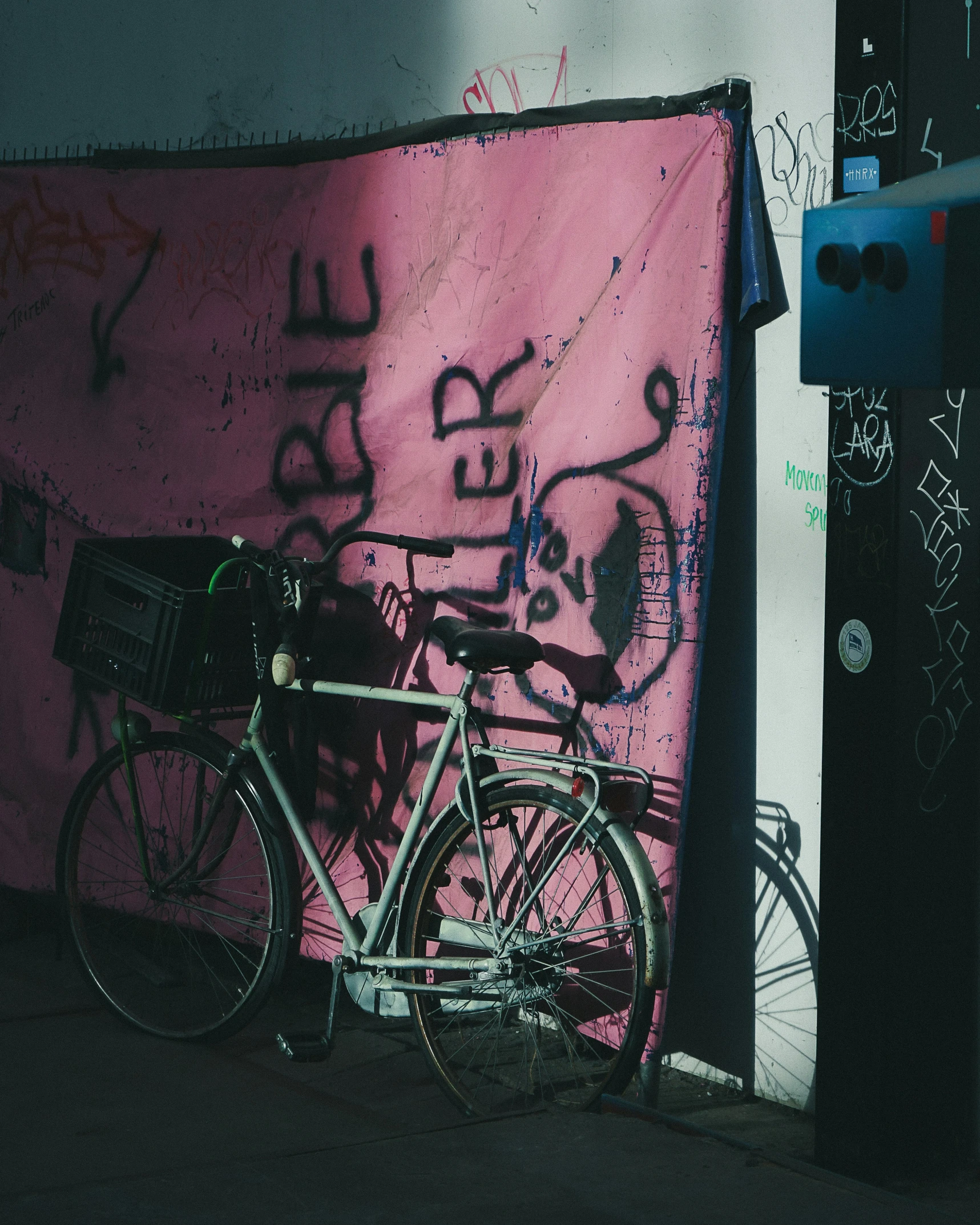 a bicycle  to a pole in front of a pink fence