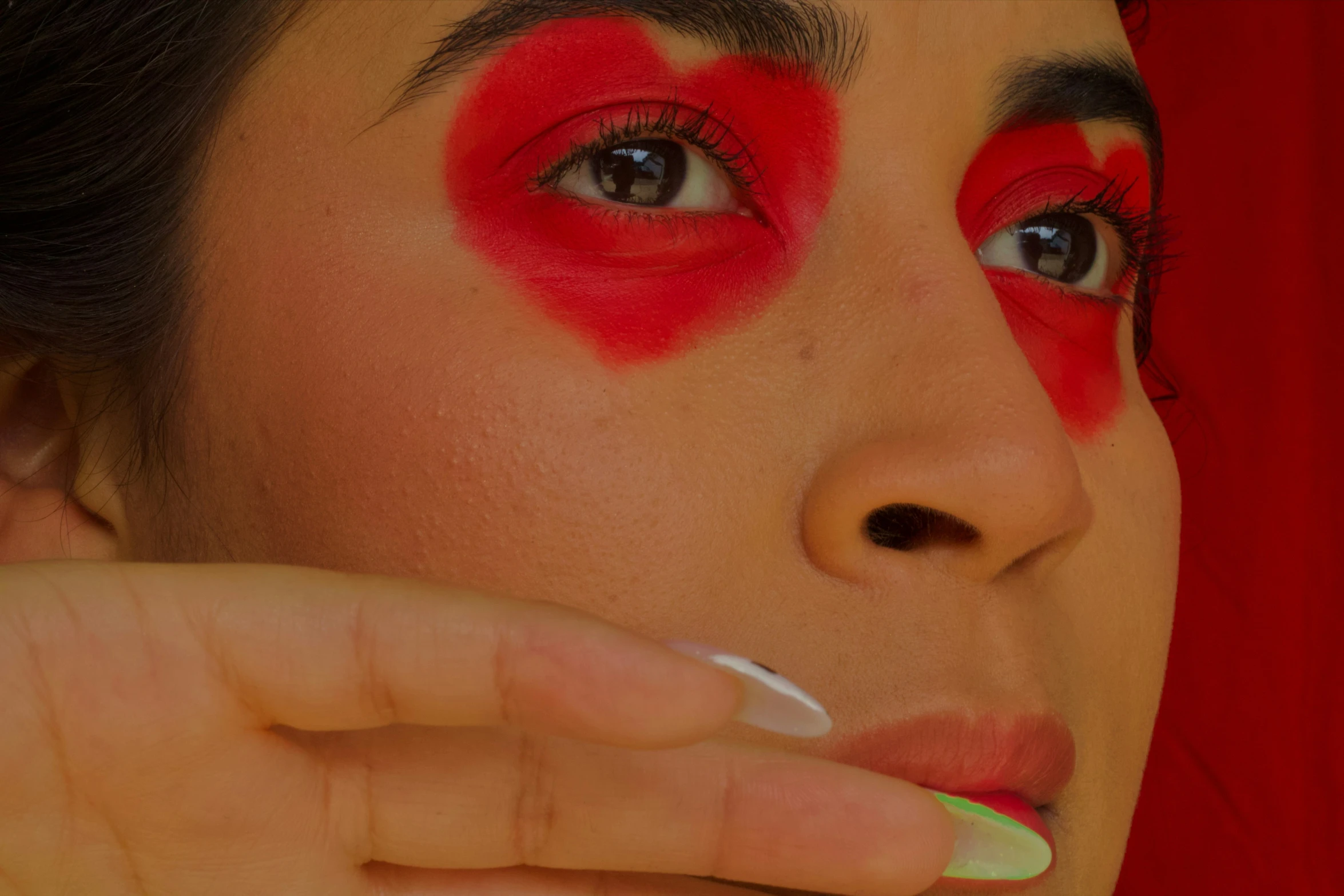 a woman with red lipstick and eyeshadow putting lipstick on her face